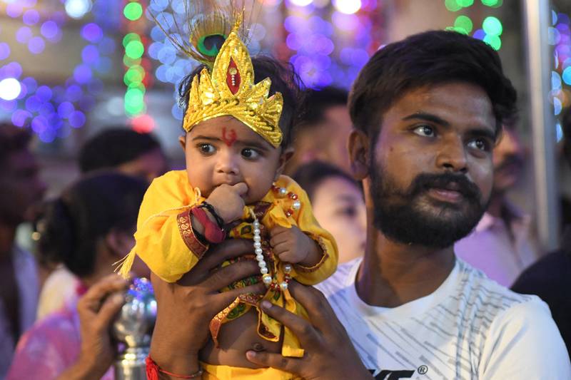 A man carries his child dressed as Krishna in Amritsar. AFP