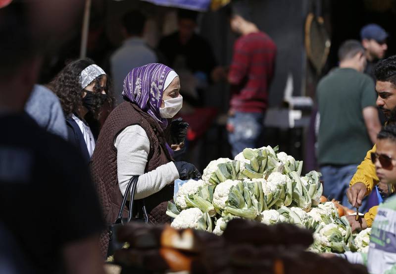 Palestinians, some wearing protective masks, shop at a fruit and vegetables market during the Muslim holy month of Ramadan amid the COVID-19 pandemic, in the occupied West Bank city of Ramallah on April 26, 2020. / AFP / ABBAS MOMANI
