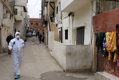 A health worker dressed in a protective outfit walks in an alley at the Wavel Palestinian refugee camp in Lebanon's eastern Bekaa Valley. AFP
