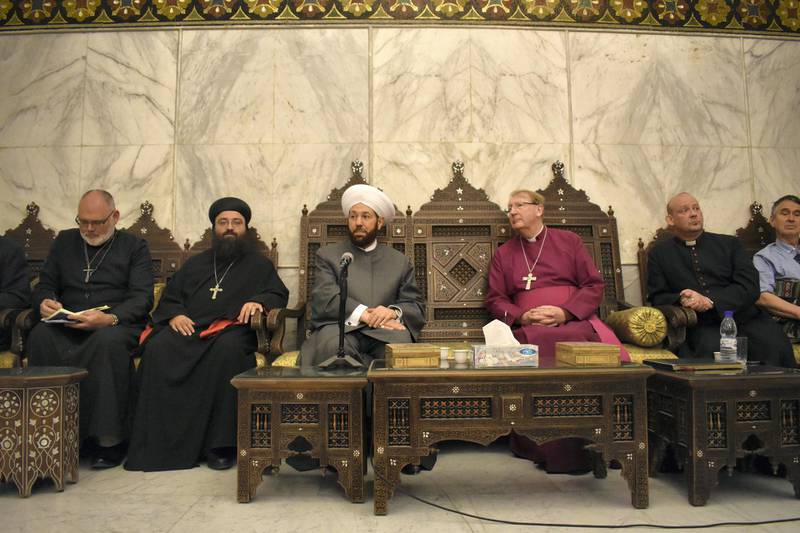 <p>Reverend Andrew Ashdown, left,&nbsp;and Michael Langrish, Former Bishop of Exeter, sit alongside the Grand Mufti of Syria who is believed to be responsible for authorising the executions of thousands of Syrian prisoners. Gareth Browne / The National</p>
