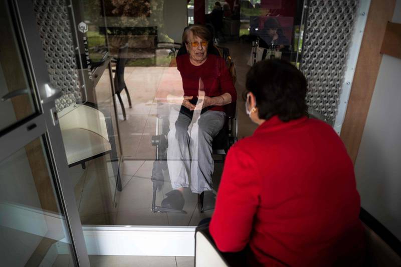 A woman speaks with her mother in a visiting room fitted with window during a visit in an accommodation facility for dependent elderly on April 21, 2020, in Toulouse, France. AFP