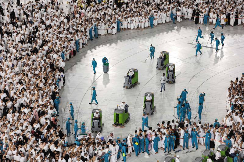 Muslims wait to pray as cleaning staff disinfect the grounds at the Grand Mosque in Makkah