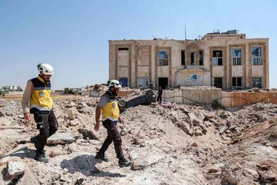 Members of the Syrian Civil Defence, also known as the "White Helmets", walk in the rubble outside a health facility that was hit by a reported Russian air strike after midnight in town of Urum al-Kubra in the western countryside of Syria's northern Aleppo province just before a truce went into effect, on August 31, 2019. Air strikes on Syria's northwestern Idlib region stopped on August 31, a war monitor said, after the government agreed to a Russian-backed ceasefire following four months of deadly bombardment. The truce is the second such agreement since an August 1 ceasefire deal broke down only days after going into effect, prompting Damascus and regime ally Moscow to resume bombardment. / AFP / Omar HAJ KADOUR
