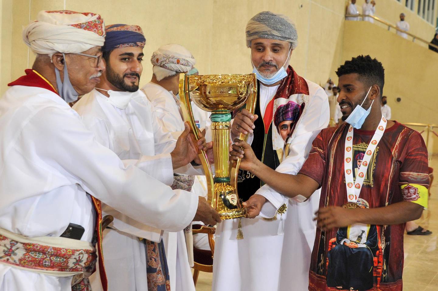 Omani Minister of Sport Sayyid Dhi Yazan bin Haitham (2nd-L) presents the trophy to Dhofar players after winning the Sultan Qaboos Cup final between Dhofar and Al-Orouba at the Rustaq Sports Complex west of the Omani capital Muscat on November 29, 2020. / AFP / Haitham AL-SHUKAIRI
