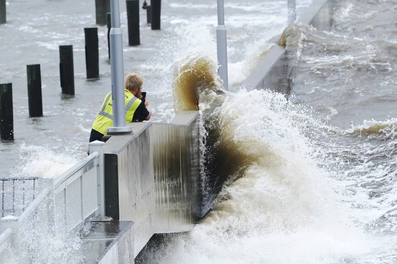 A utility worker photographs waves as they slam against a sea wall in Bay Saint Louis, Mississippi. AP