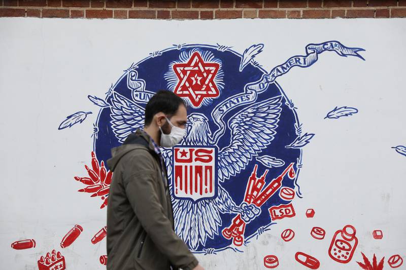 A man wearing a face mask walks past a wall of the former U.S. Embassy with anti-America images on it, in Tehran, Iran November 8, 2020. Majid Asgaripour/WANA (West Asia News Agency) via REUTERS ATTENTION EDITORS - THIS IMAGE HAS BEEN SUPPLIED BY A THIRD PARTY.