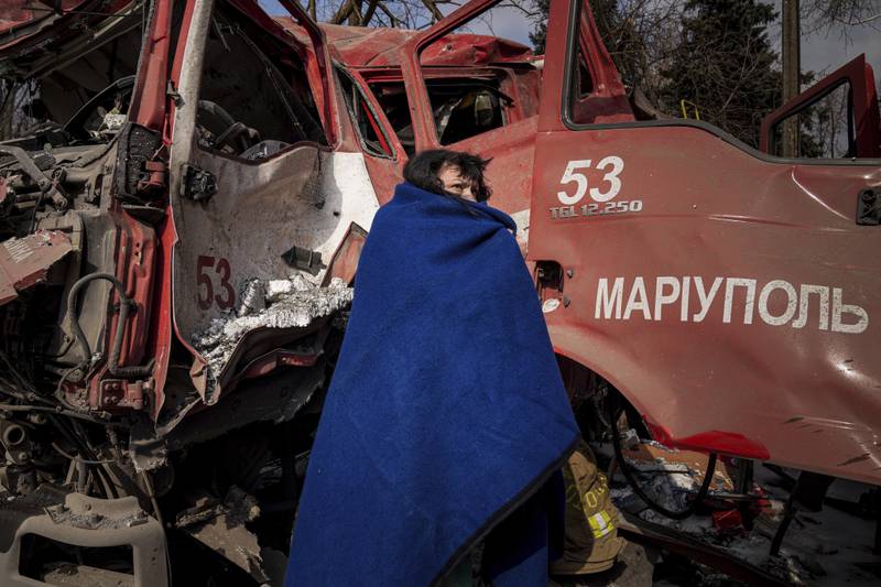 A woman covers herself with a blanket near a damaged fire truck after shelling in Mariupol, Ukraine. AP Photo