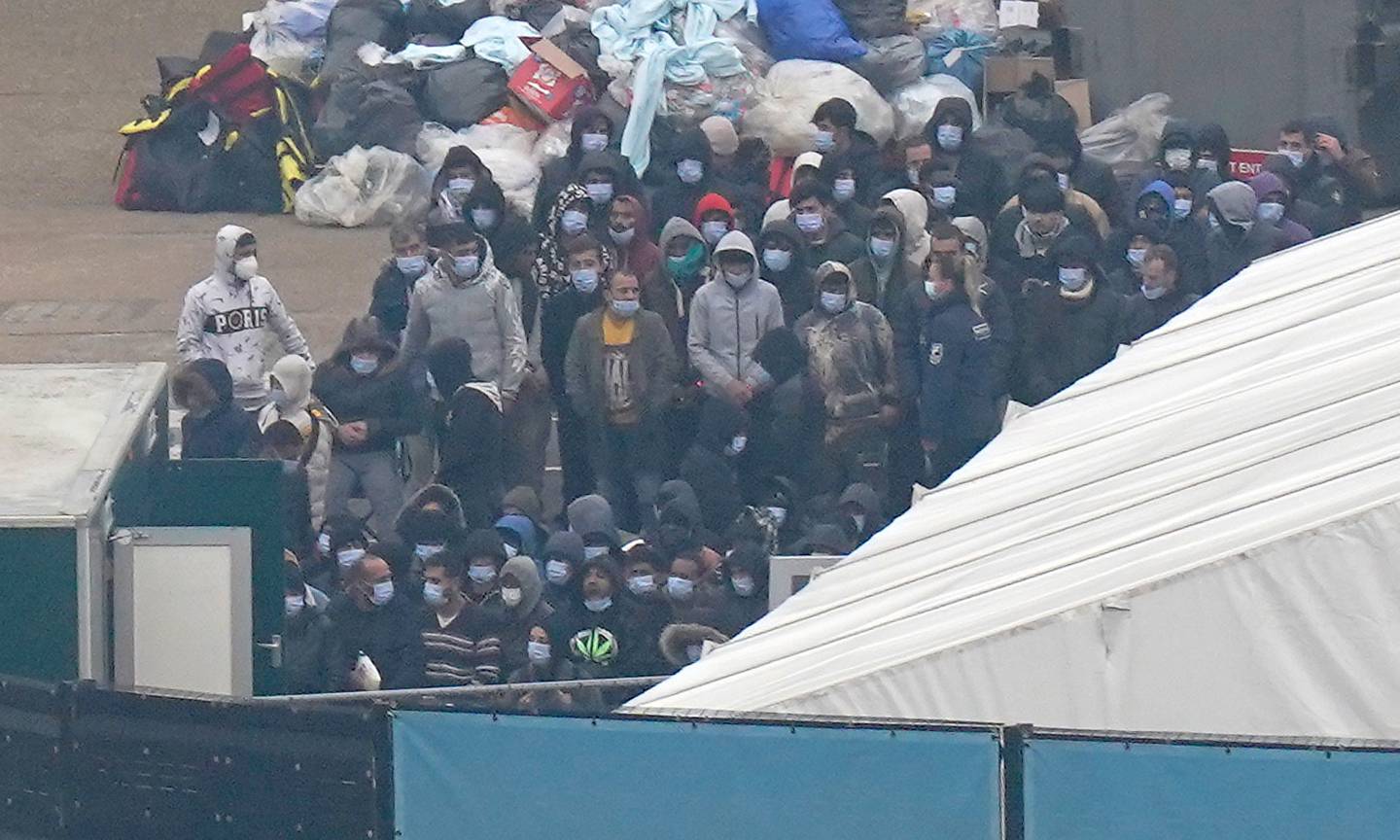 Migrants wait to be processed after arriving in Dover. The UK government classes funding for hosting migrants as foreign aid. PA 
