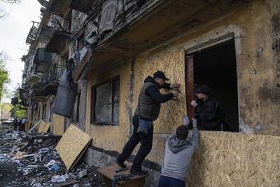 Residents board-up windows of a damaged apartment building with plywood after Russian shelling in Dobropillya, Donetsk region. AP