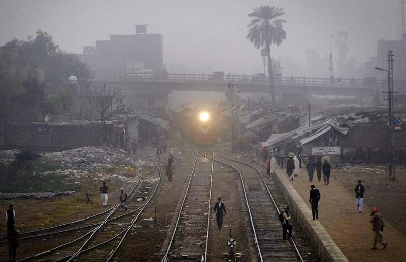 A commuter train uses lights to clear the track crossing by residents on a foggy morning in Peshawar. Mohammad Sajjad / AP Photo