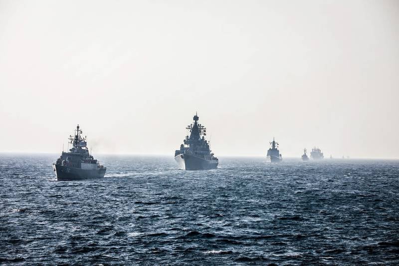 Military vessels sail in a row during the naval exercise.