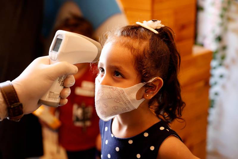 A girl wearing a mask has her body temperature checked while she arrives with her family at a beach side cafe in Gaza City, October 12. Cafes and restaurants reopened under strict regulations after a month and a half of closure as the coronavirus spread in the Gaza Strip. Adel Hana / AP