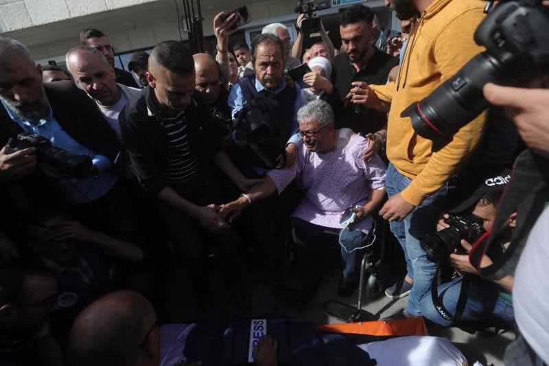 Palestinian journalists including Al Jazeera's Ali Samoudi, sitting in a wheelchair after he was shot in his back, mourn near the body. EPA