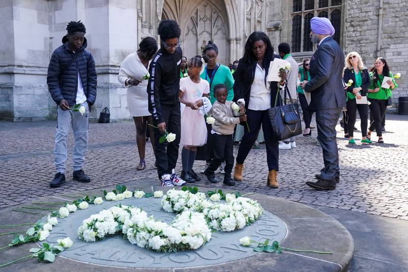 People place white roses at a memorial service for those who died in the Grenfell Tower fire, outside Westminster Abbey in London. Reuters
