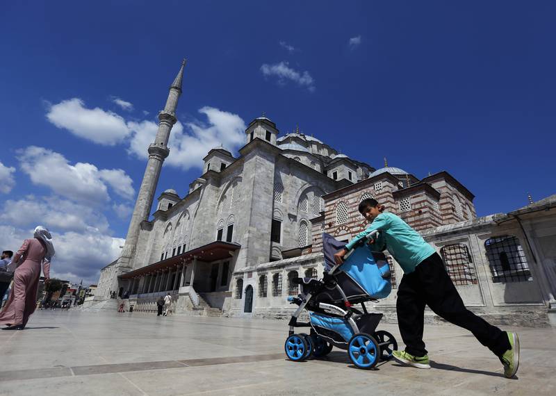 In this photo taken on Tuesday, Aug. 20, 2019, a Syrian boy pushes a pram past Fatih mosque in Istanbul. Syrians say Turkey has been detaining and forcing some Syrian refugees to return back to their country the past month. The expulsions reflect increasing anti-refugee sentiment in Turkey, which opened its doors to millions of Syrians fleeing their country's civil war. (AP Photo/Lefteris Pitarakis)