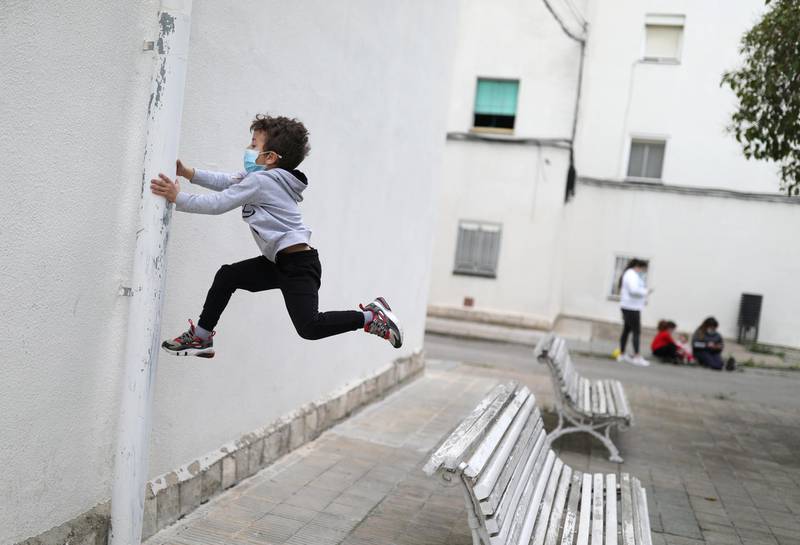 Kilian, 6, wears a protective face mask as he jumps from a bench, after restrictions were partially lifted for children, during the coronavirus disease (COVID-19) outbreak, in Igualada, Spain. REUTERS