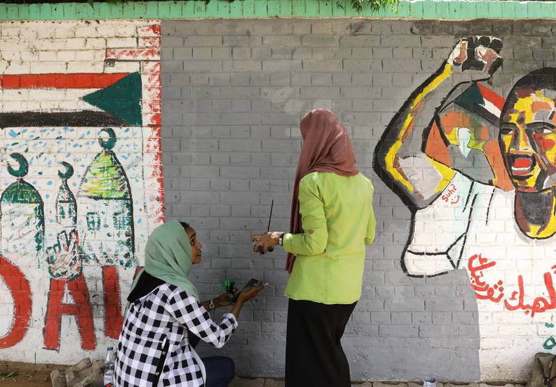 Sudanese youngsters work on repainting a mural.  EPA
