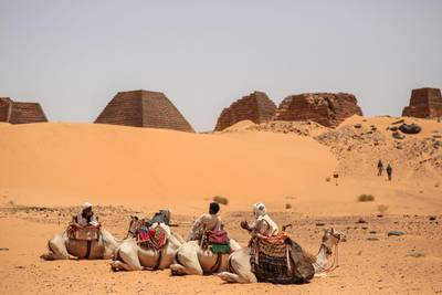 Tour guides wait for tourists to offer them camel rides at the historic Meroe pyramids. Stock photo