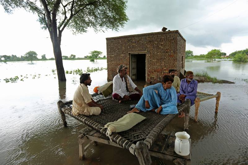 Residents sit on a charpai in a flooded area. AFP