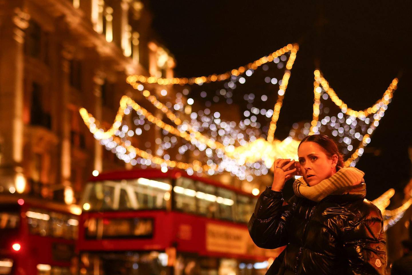 A woman holds her smartphone to her ear as she walks past Christmas lights on Regents Street amid the coronavirus disease (COVID-19) outbreak in London, Britain, November 19, 2020. REUTERS/Simon Dawson