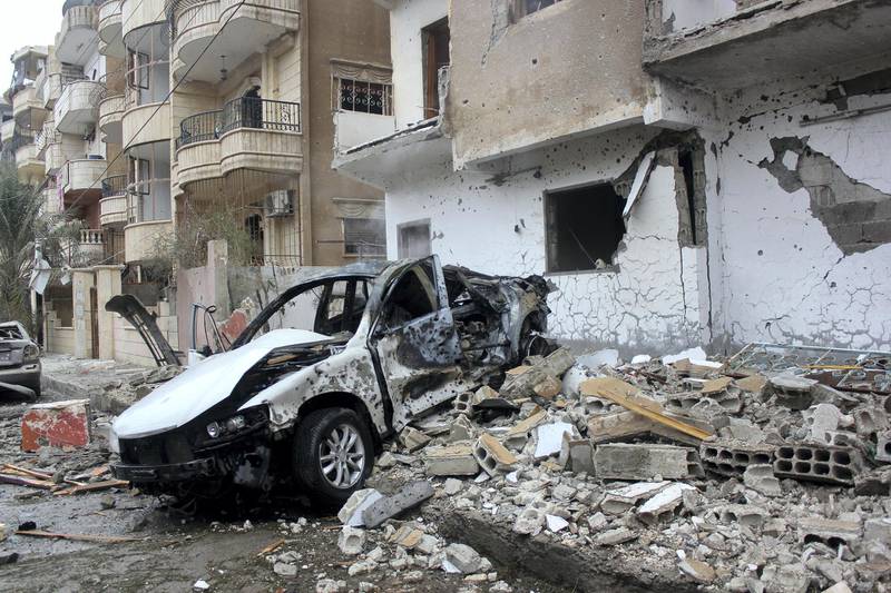The wreckage of a car sits next to debris following an alleged air strike on December 20, 2014 by regime forces on the Syrian city of Raqa, which is under the control of the Islamic State group (IS) group. The Syrian Observatory for Human Rights said regime planes carried out one strike in Raqa that killed at least seven civilians. AFP PHOTO / RMC / STR (Photo by STR / RMC / AFP)