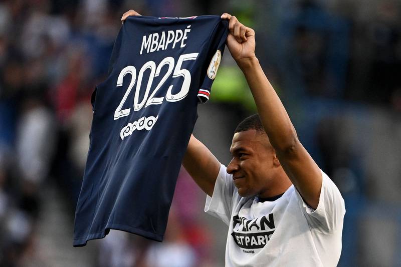 Paris Saint Germain forward Kylian Mbappe poses with a jersey after the announcement he is staying at PSG until 2025. AFP