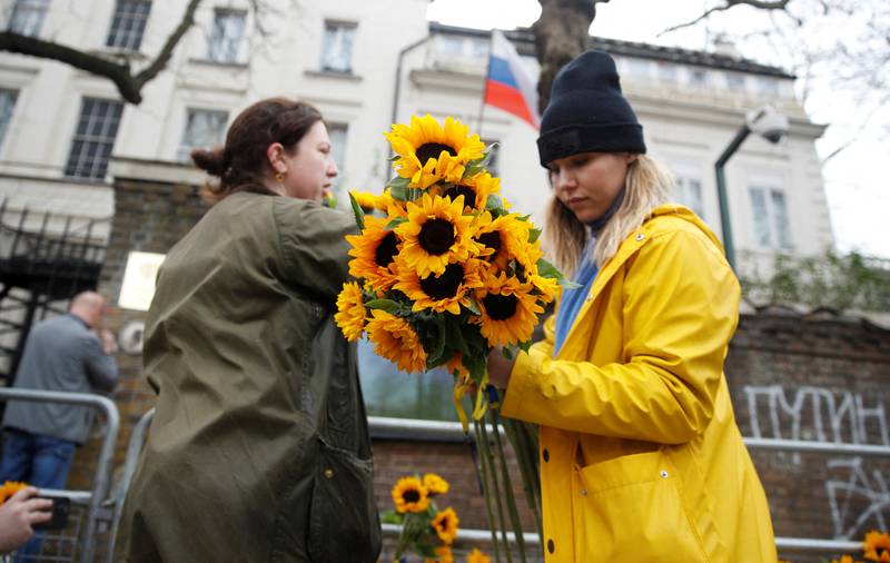 Anti-war protesters attach sunflowers to barriers in front of the Russian embassy. Reuters