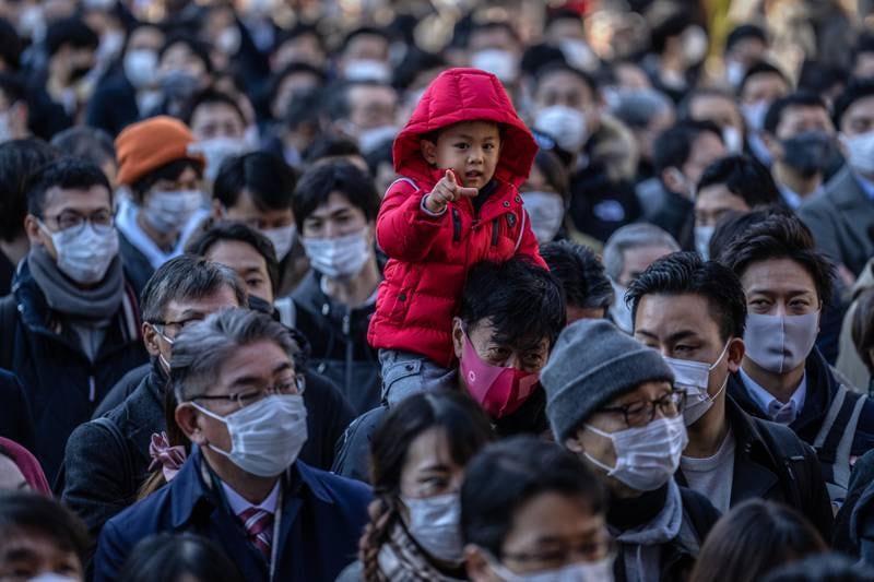 Perched on his father's shoulders, a boy joins masked Japanese workers as they queue to offer prayers on the first business day of the year at the Kanda Myojin shrine Tokyo. Getty