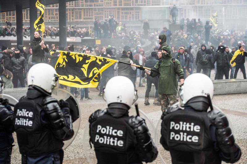 TOPSHOT - Demonstrators clash with Belgian riot police during a march in Brussels on December 16, 2018 called by the right-wing Flemish party Vlaams Belang and a dozen of organisations against the UN Marrakech global compact on migration, signed last week by the Belgian Prime Minister.  Brussels' Mayor forbade the venue of this march but State council ruled against that decision and the march was authorized. A counter march of Solidarity is also planned.   - Belgium OUT
 / AFP / Belga / JONAS ROOSENS
