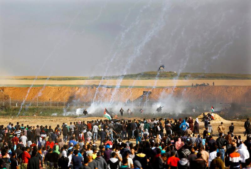 Palestinians run for cover from tears gas fired by the Israelis. Mohammed Abed / AFP