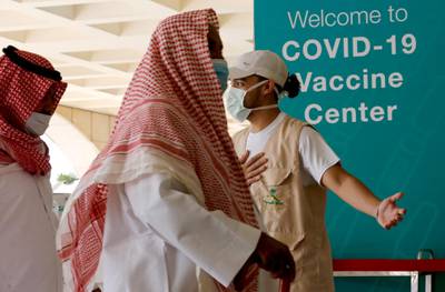 Saudis are greeted by a health worker as they enter a new coronavirus vaccination center at the Jiddah old airport, Saudi Arabia, Thursday, Jan. 14, 2021. The Saudi Ministry of Health has called on citizens and residents to take the vaccine for free. (AP Photo/Amr Nabil)