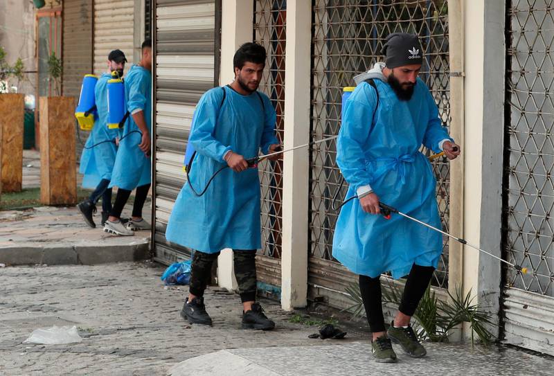 Iraqi volunteers spray disinfectant as a precaution against the coronavirus during a curfew, in a market in Baghdad, Iraq. AP Photo
