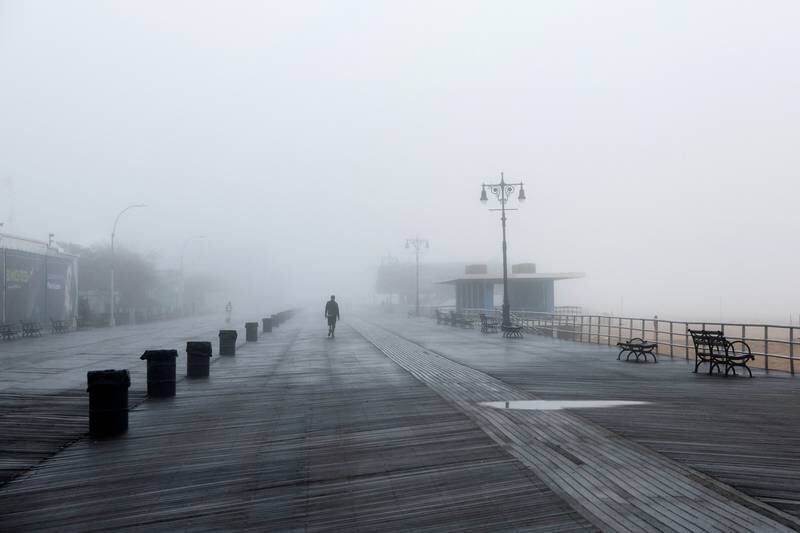 A man walks on the Coney Island boardwalk during a foggy morning in the Brooklyn borough of New York City. Reuters