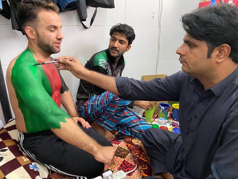 Pakistani painter Faisal Mahboob helps Rahim Sediqi get ready to support Afghanistan at his apartment in Hor Al Anz. Paul Radley / The National