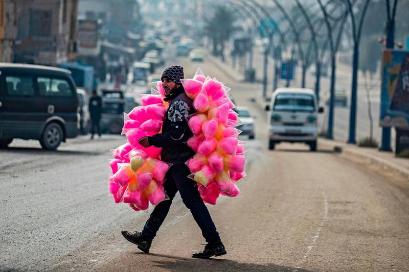 A street vendor selling cotton candy crosses a road in the northern Syrian city of Raqa, the former Syrian capital of ISIS. The Kurdish-led Syrian Democratic Forces overran Raqa in 2017, after years of what residents described as ISIS' brutal rule, which included public beheadings and crucifixions. AFP