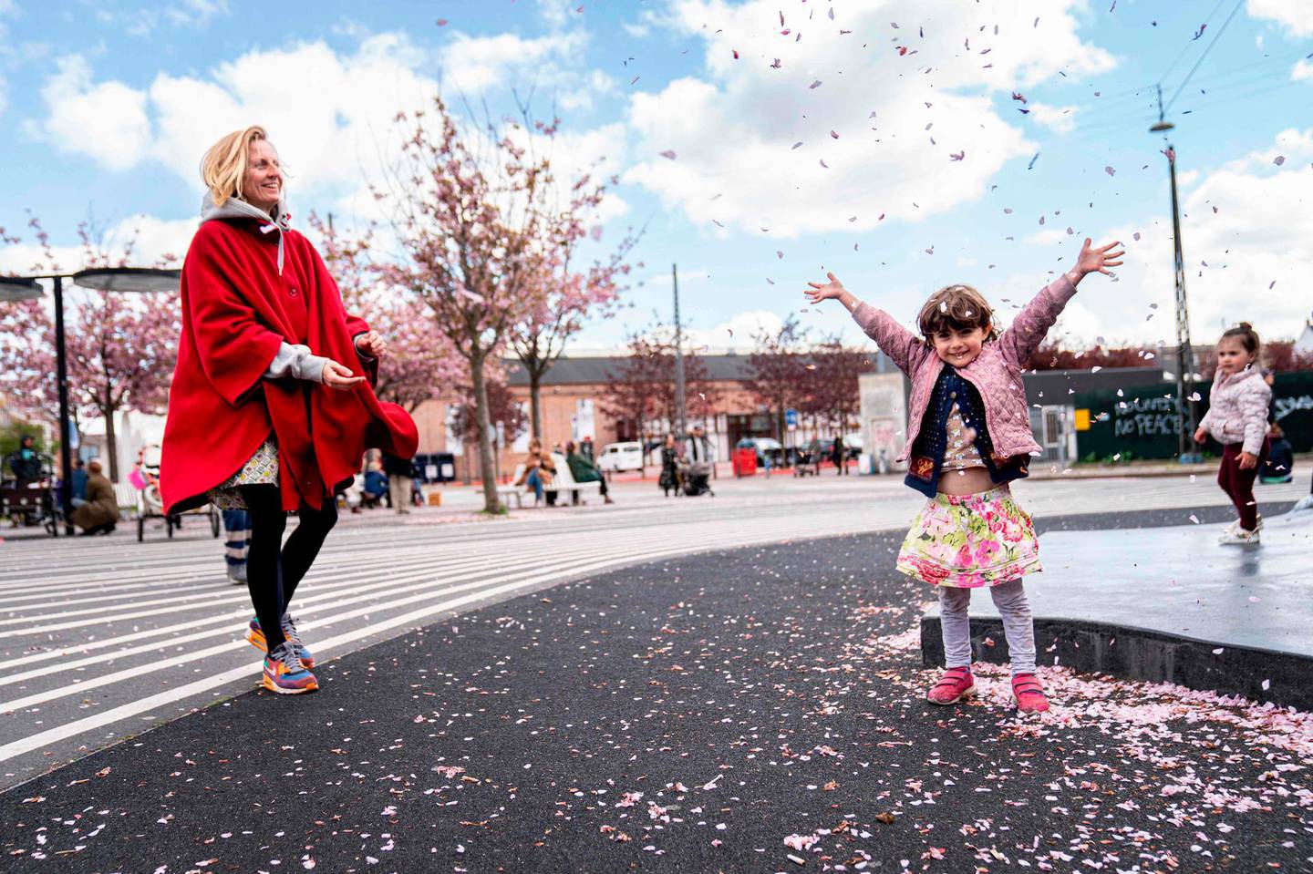 Evi Kjaer Everloeff throws the petals of the Japanese cherry trees in the air with her mother Rikke Kjaer at the Black Square in Copenhagen, on May 3, 2020 as the cherry trees are in full bloom. Denmark OUT
 / AFP / Ritzau Scanpix / Ida Guldbaek Arentsen
