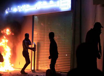 A demonstrator is seen next to a burning fire in front of a bank during a protest against growing economic hardship in Sidon, Lebanon. Reuters