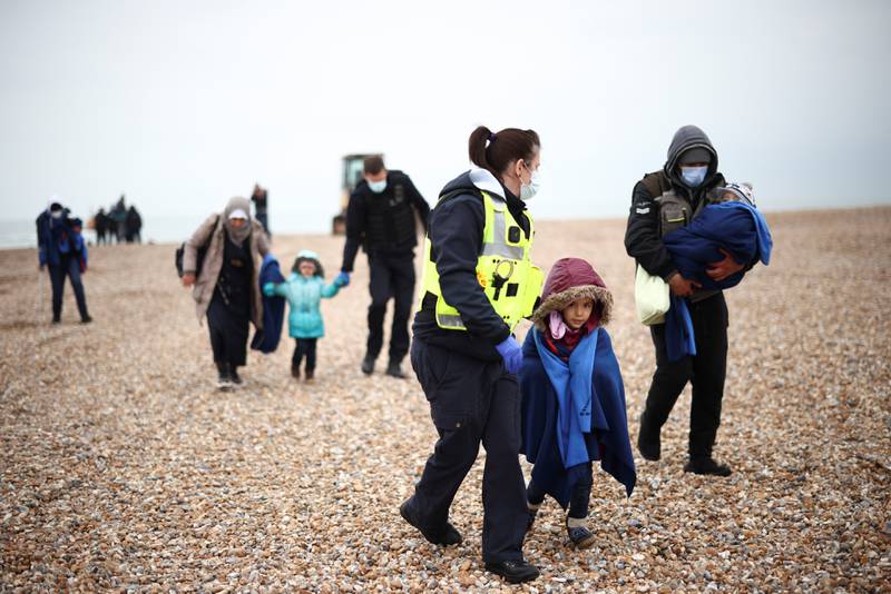 Migrants are escorted by Border Force staff in Dungeness, after being brought ashore by an RNLI lifeboat. Reuters