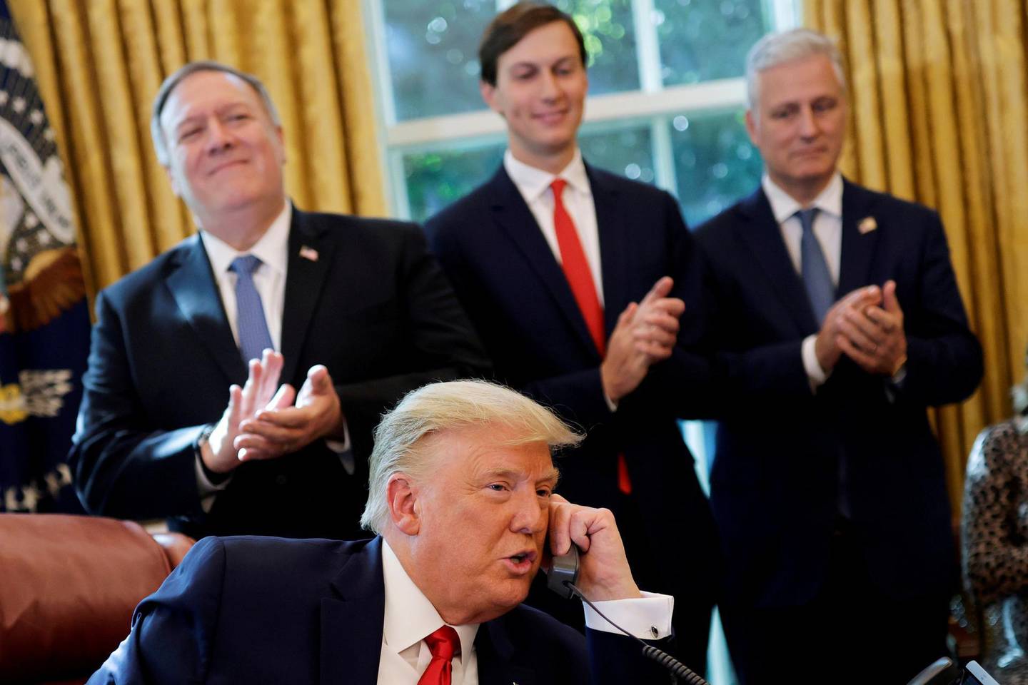 FILE PHOTO: Secretary of State Mike Pompeo and White House senior adviser Jared Kushner applaud as U.S. President Donald Trump is seen on the phone with leaders of Israel and Sudan speaking about the decision to rescind Sudan's designation as a state sponsor of terrorism, in the Oval Office at the White House in Washington, U.S., October 23, 2020. REUTERS/Carlos Barria/File Photo