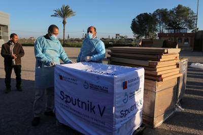 Palestinian health workers stand next to a shipment of Russia’s Sputnik V vaccine donated by the UAE. Reuters