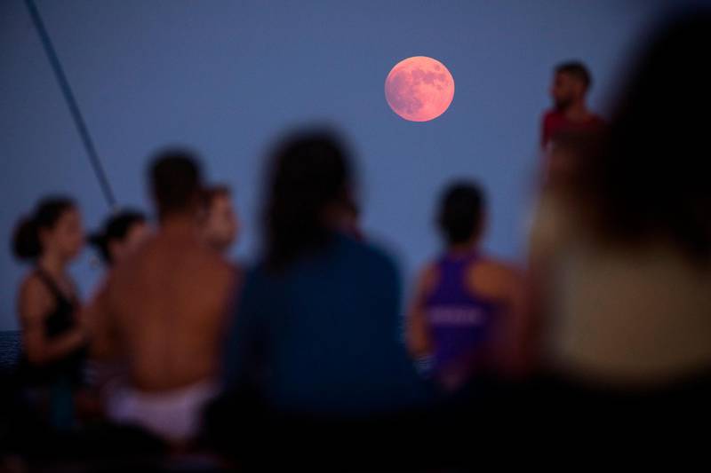 A partial lunar eclipse is visible as men and women take part in a yoga session in front of the Mediterranean sea in Barcelona, Spain. AP Photo/Emilio Morenatti