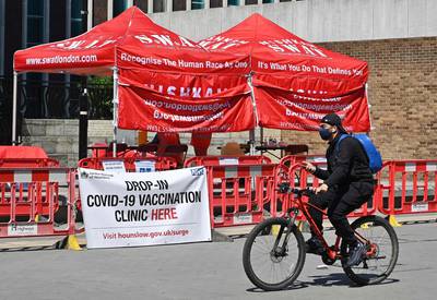 A cyclist rides past a Covid-19 vaccine drop-in vaccination clinic, in Hounslow, west London. AFP