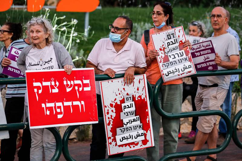 Demonstrators gather with signs reading Arabic and Hebrew "Arab blood is not cheap" (C, R) and in Hebrew "seek and pursue justice", during a protest by Arab Israelis and activists against the government's insufficient action towards rising violence levels within the Arab community, outside the home of Public Security Minister Omer Bar-Lev in the northern Israeli town of Kokhav Yair.  AFP