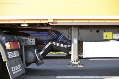 A migrant sits under the trailer of a lorry as he attempts to cross the English Channel, in Calais, northern France to Britain on Wednesday, June 24, 2015. Thibault Camus/AP Photo