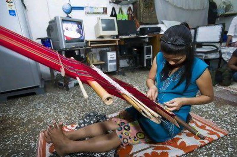 Muanpuii, a 35-year-old Burmese refugee from the Falam tribe in the Chin state of Burma, weaves using a hand loom in Vikaspuri, New Delhi.