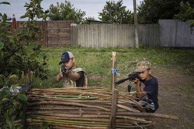 Maksym and Andrii with plastic guns at a 'checkpoint' they set up while playing in Kharkiv, July 2022. AP