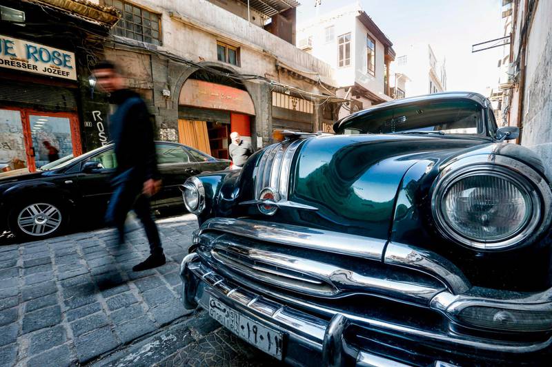 A man walks past a 1954 Pontiac Star Chief classic automobile parked along a cobbled road in the Bab Sharqi district of the old city of the Syrian capital Damascus.  AFP