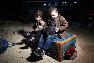 Children sit on a suitcase following the arrival of buses carrying Jaish al-Islam fighters and their families from the former rebel bastion's main town of Douma at the Abu al-Zindeen checkpoint controlled by Turkish-backed rebel fighters near the northern Syrian town of al-Bab, after they were evacuated from the last rebel-held pocket in Eastern Ghouta on April 3, 2018.
Russia-backed regime forces have retaken control of 95 percent of Eastern Ghouta since February 18 through a combination of a deadly air and ground assault and evacuation deals. / AFP PHOTO / Nazeer al-Khatib