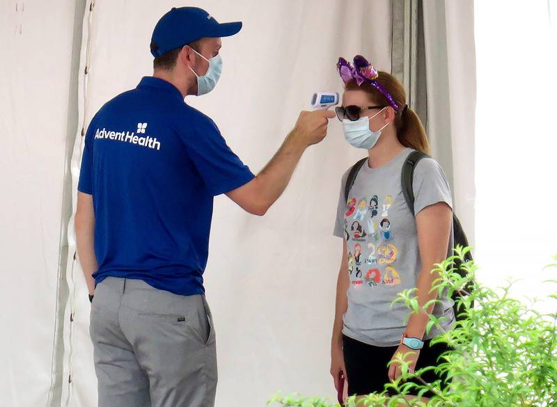 A guests gets her temperature taken before entering the official reopening day of the Magic Kingdom at Walt Disney World. AP