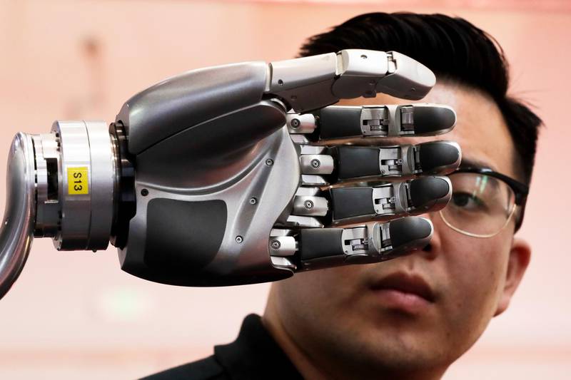 FILE - In this Aug. 23, 2017, file photo, a visitor looks at a robotic hand powered by Kinfinity Glove, developed by the German Aerospace Center, on display at the World Robot Conference at the Yichuang International Conference and Exhibition Centre in Beijing. Chinaâ€™s government has appealed to Washington to accept its industrial progress after U.S. intelligence officials said Beijing helps to steal and copy foreign technologies. (AP Photo/Andy Wong)